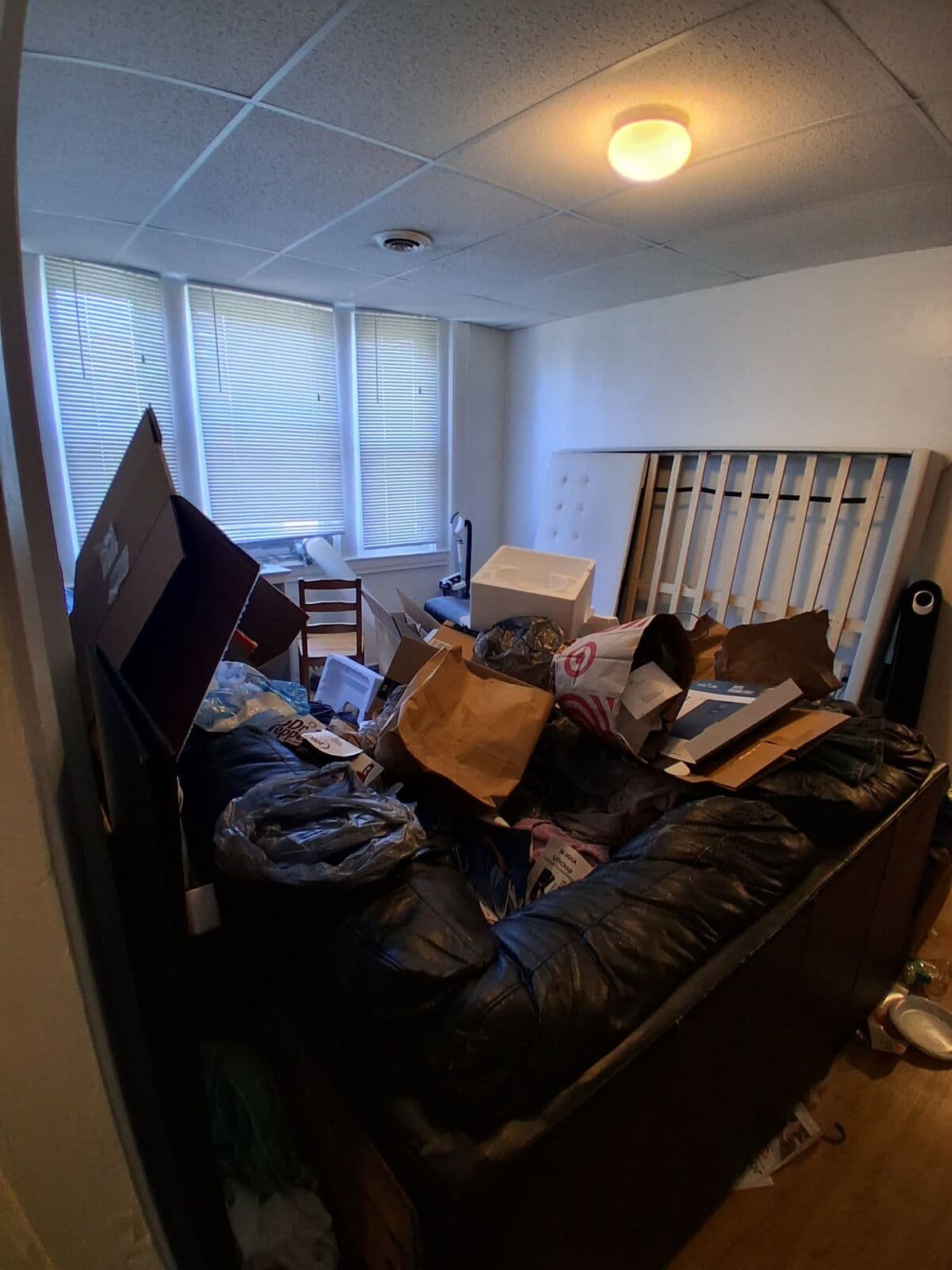 Before: Apartment room with a couch piled high with bags and boxes