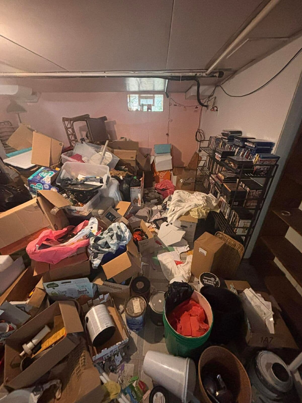Before: Wide view of the basement floor covered in clutter