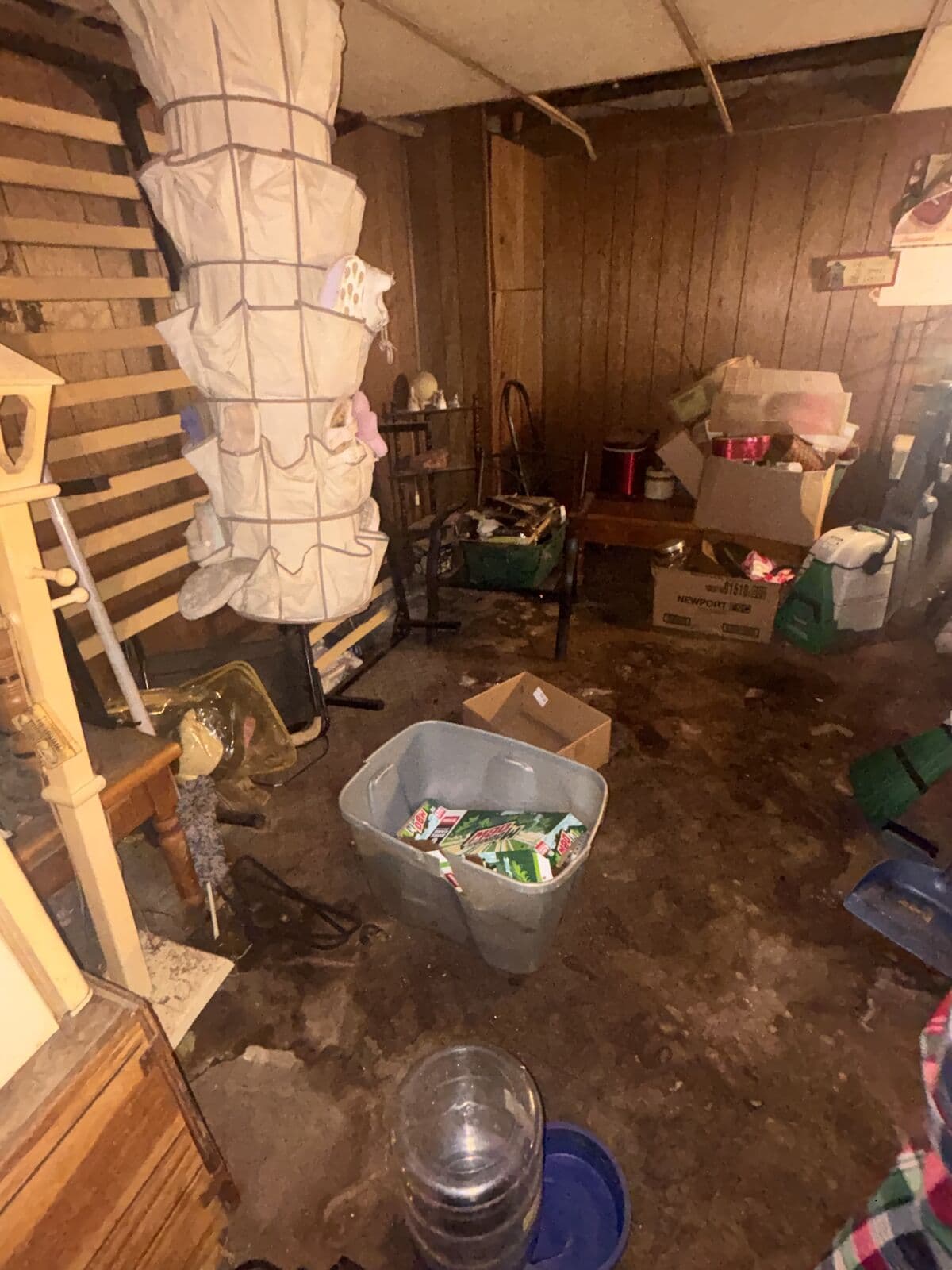 Before: Paneled basement with clutter and stained floor