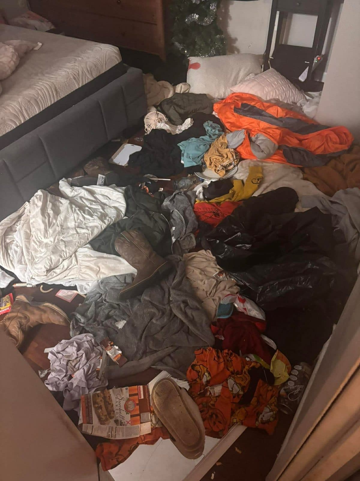 Before: Bedroom floor buried in piles of clothes, bags and bedding beside the bed