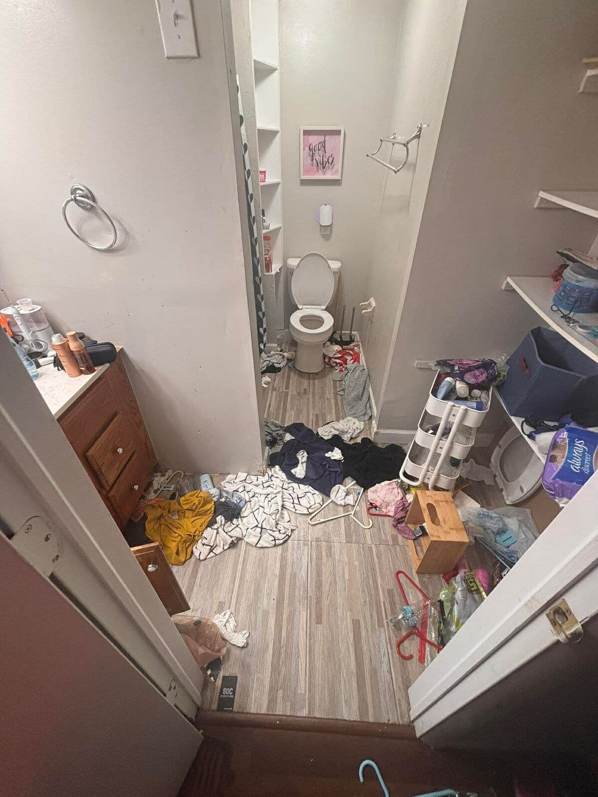 Before: Bathroom floor covered in clothes and clutter