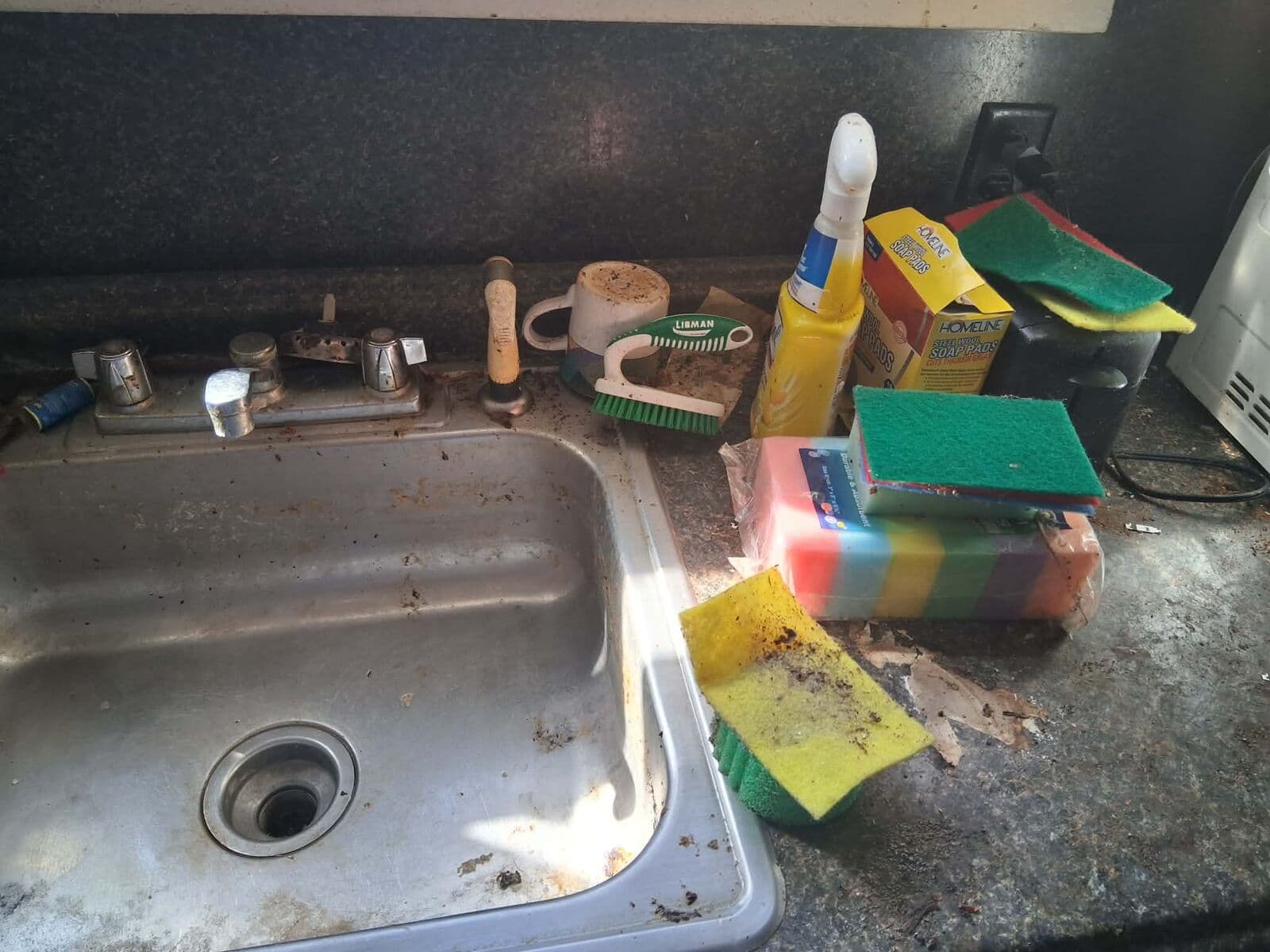 Before: Grimy kitchen sink and counter covered in dirty sponges and debris