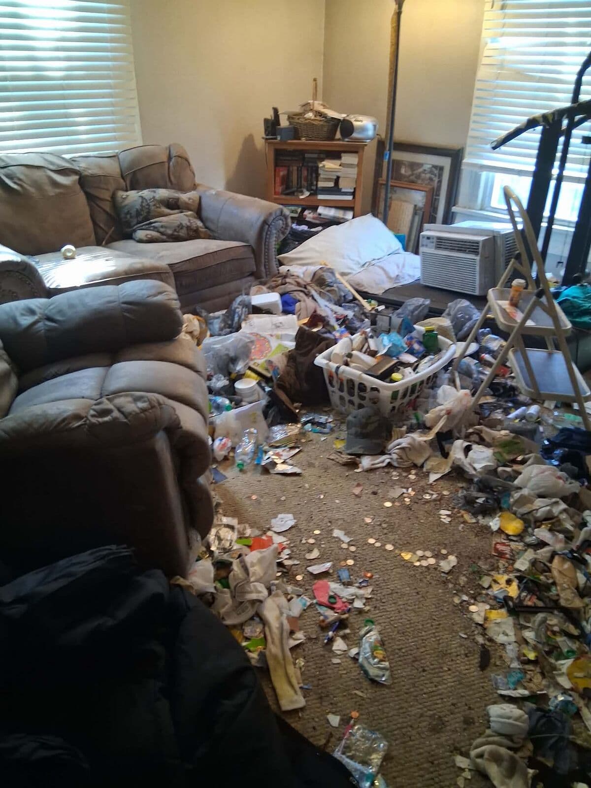 Before: Living room floor buried in trash and clothing around a sofa