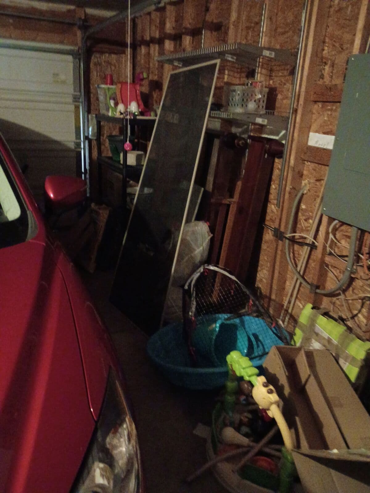 Before: Garage wall crowded with stored items beside a car