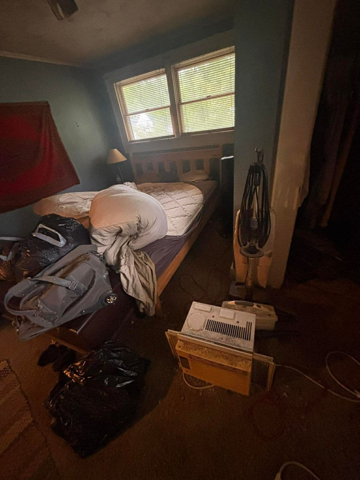 Before: Bedroom crowded with clothing, bags and boxes