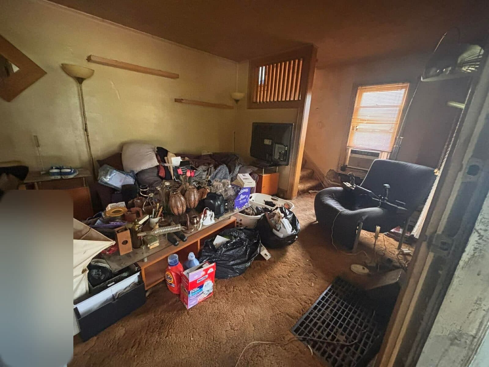 Before: Living room crowded with furniture and belongings